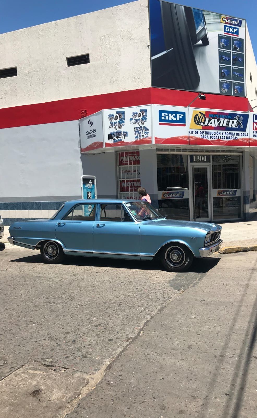 Un auto clásico estacionado frente a Repuestos Javier