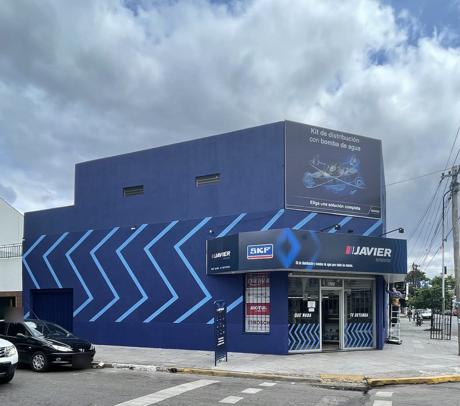 Esquina del local de Repuestos Javier con la fachada azul y el cartel de kits de distribución